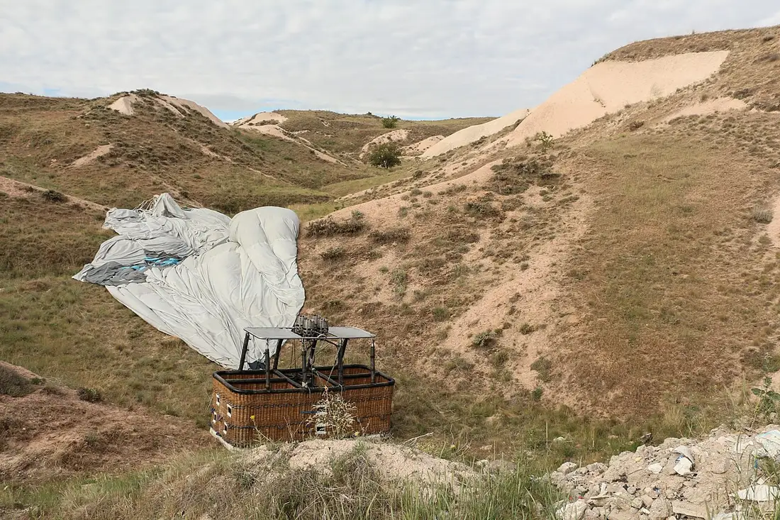 Deflated hot-air balloon and wicker basket on the ground in Cappadocia.