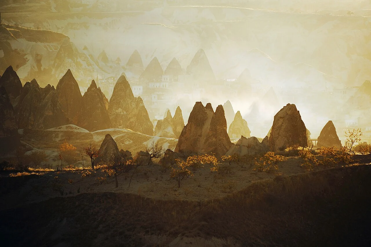 Golden sunset light and haze around fairy chimneys in Göreme Valley, Cappadocia.