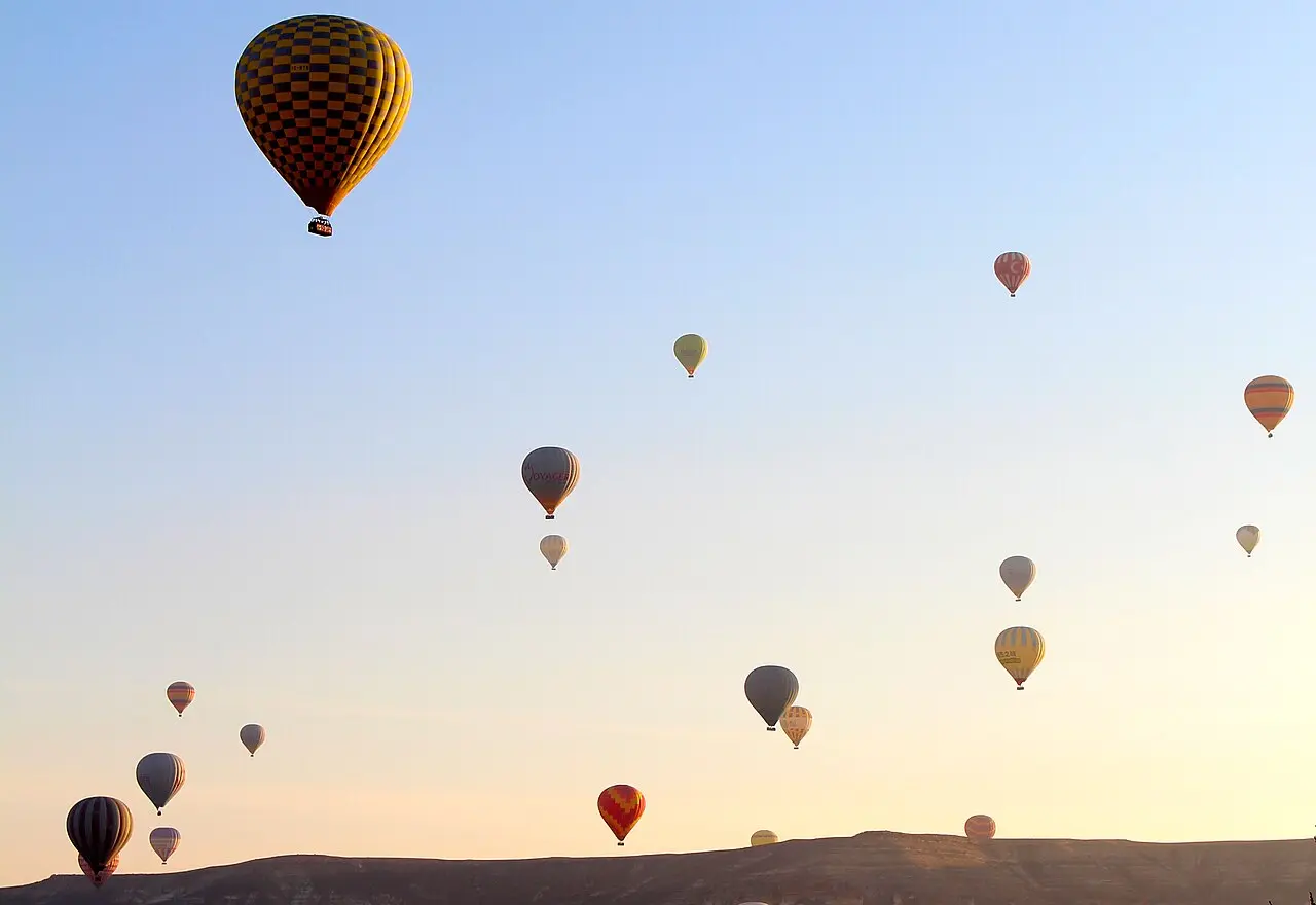 Hot-air balloons scattered across the morning sky in Cappadocia.